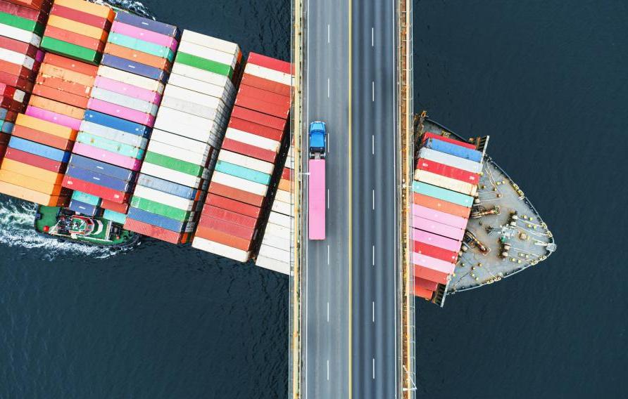 Shipping container sailing under a bridge